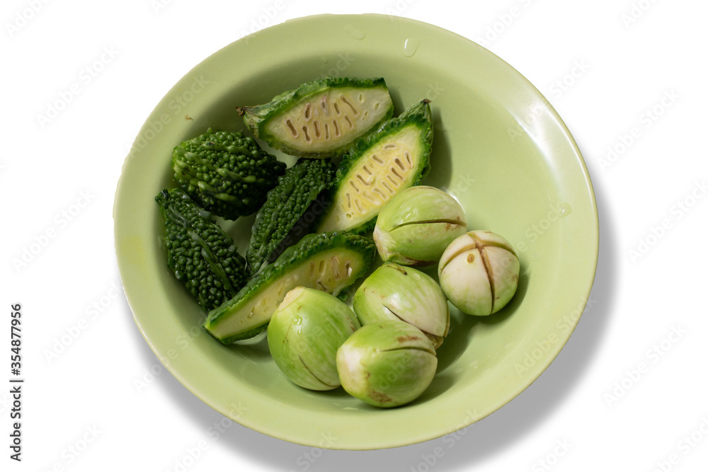 Bitter gourds and green eggplants are on the green bowl isolated on white background. Bitter gourds and green eggplants are on the green bowl isolated on white background.