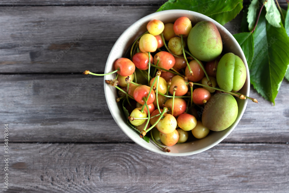 flat lay, plate with green cherries and apricots, wooden surface copy space. flat lay, plate with green cherries and apricots, wooden surface copy space.