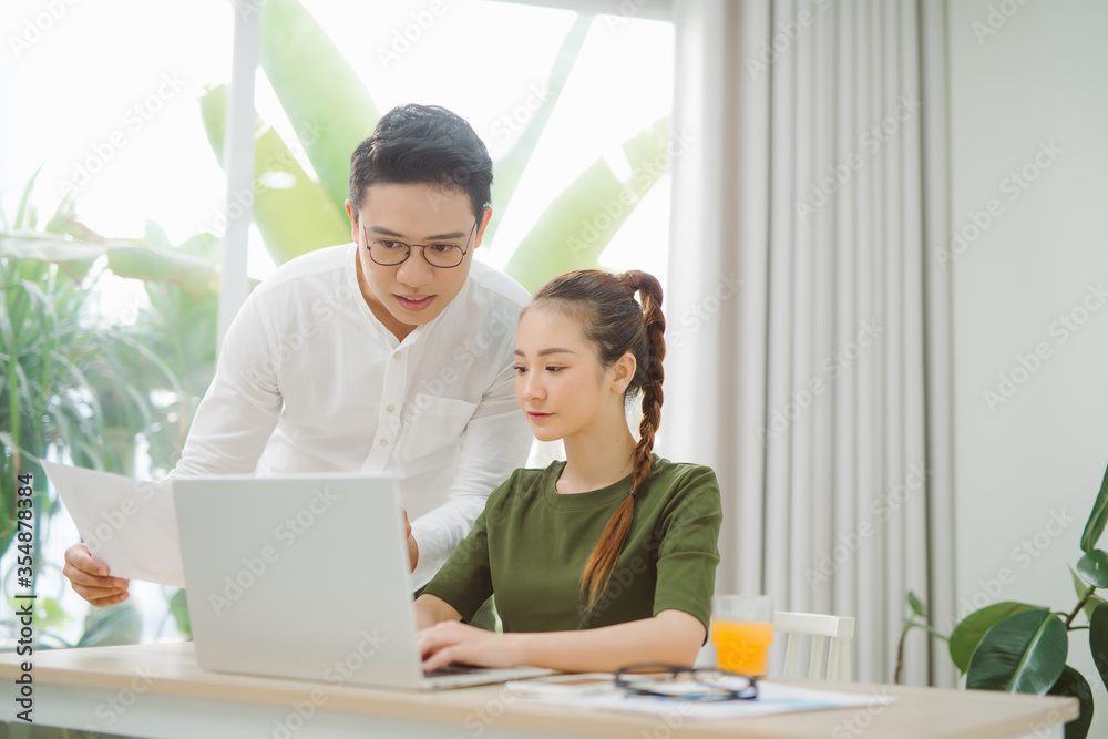 Wide shot of smiling couple surfing in laptop sitting at table Wide shot of smiling couple surfing in laptop sitting at table