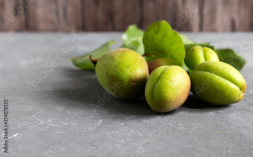 closeup green apricots with batva and leaves, organic products on concrete background, copy space.