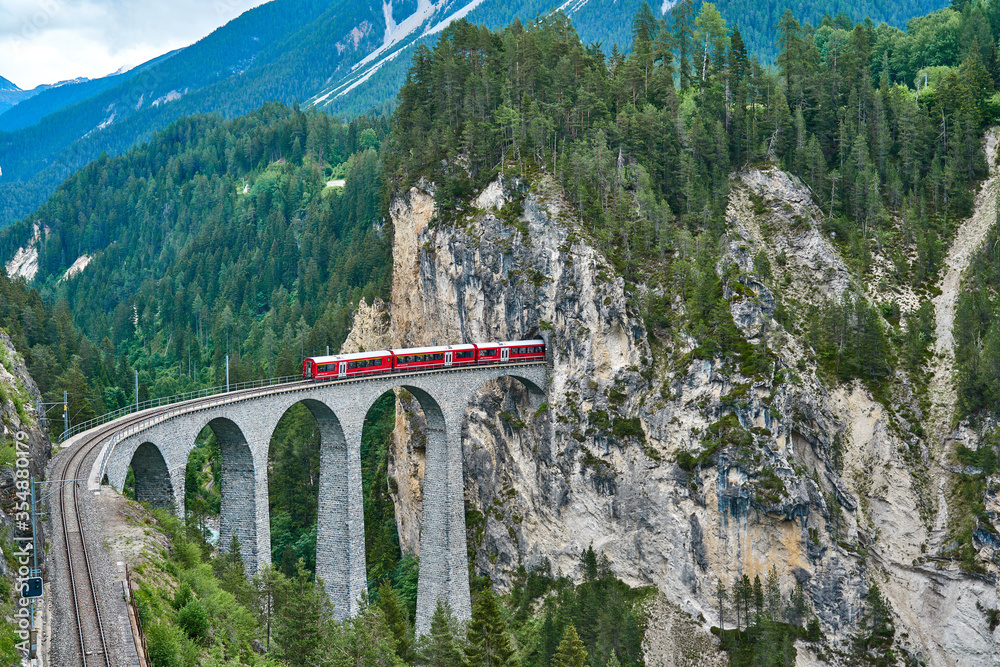 Red train passes above the Landwasser Viaduct bridge, in canton of ...