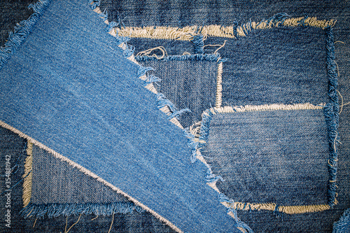 Destroyed torn denim blue jeans fabric frame on blue jeans background. Worn Jeans Casual Double Color patch Denim.