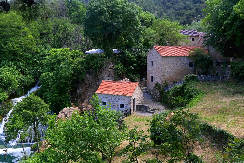 Old traditional watermill on river Krka in National Park Krka, Croatia. Beautiful watrefalls in the background. Krka is popular summer travel destination.