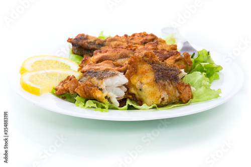 fried hake fish in batter with lettuce and lemon in a plate