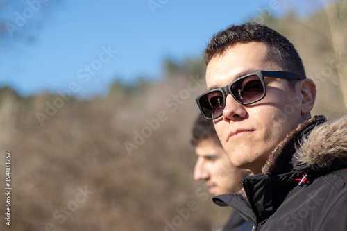 Young adult man wearing black sunglasses and a jacket on a cold winter day looking straight at the camera, hiking mountains of Bosnia and Herzegovina