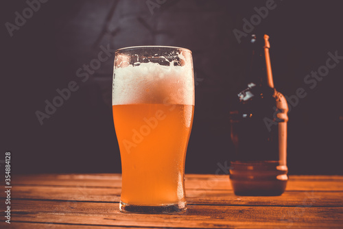Glass of cold pale beer placed on a rustic wooden table
