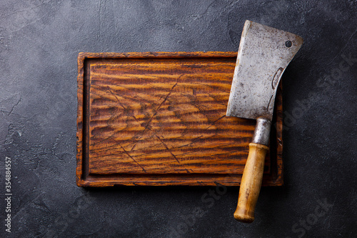 Wooden cutting board with cleaver. Dark background. Copy space. Top view.