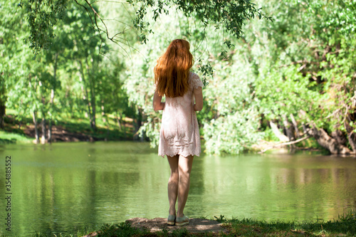 Portrait of a young beautiful woman in white dress posing by the lake