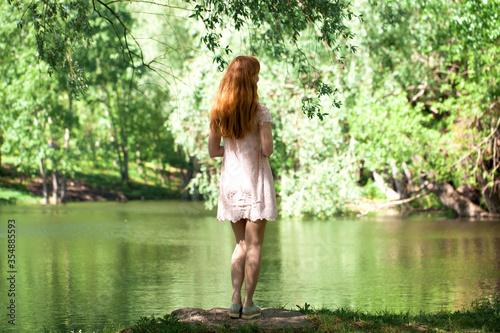 Portrait of a young beautiful woman in white dress posing by the lake