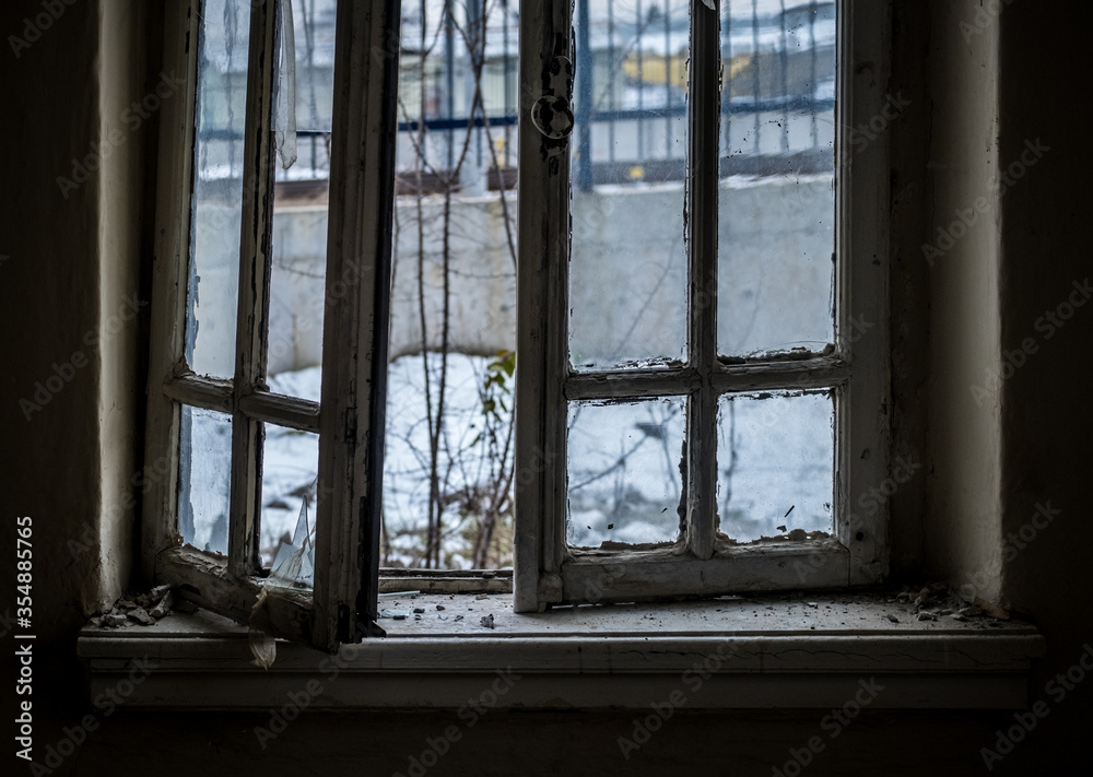 Fototapeta premium Window of an empty abandoned old building with broken glasses
