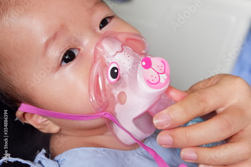 Sick boy inhalation therapy by the mask of inhaler. Boy is sick with Respiratory Syncytial Virus. Patient Boy use inhalation with Nebulizer mask at hospital. The baby are spraying bronchodilators .