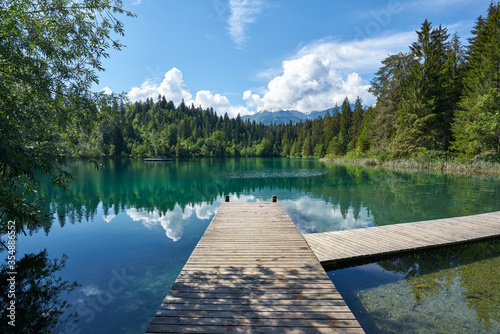Landscape panorama of Crestasee - Lake Cresta in June, municipalities of Flims and Trin in the Grisons, Switzerland. Wooden dock on the lake.       photo