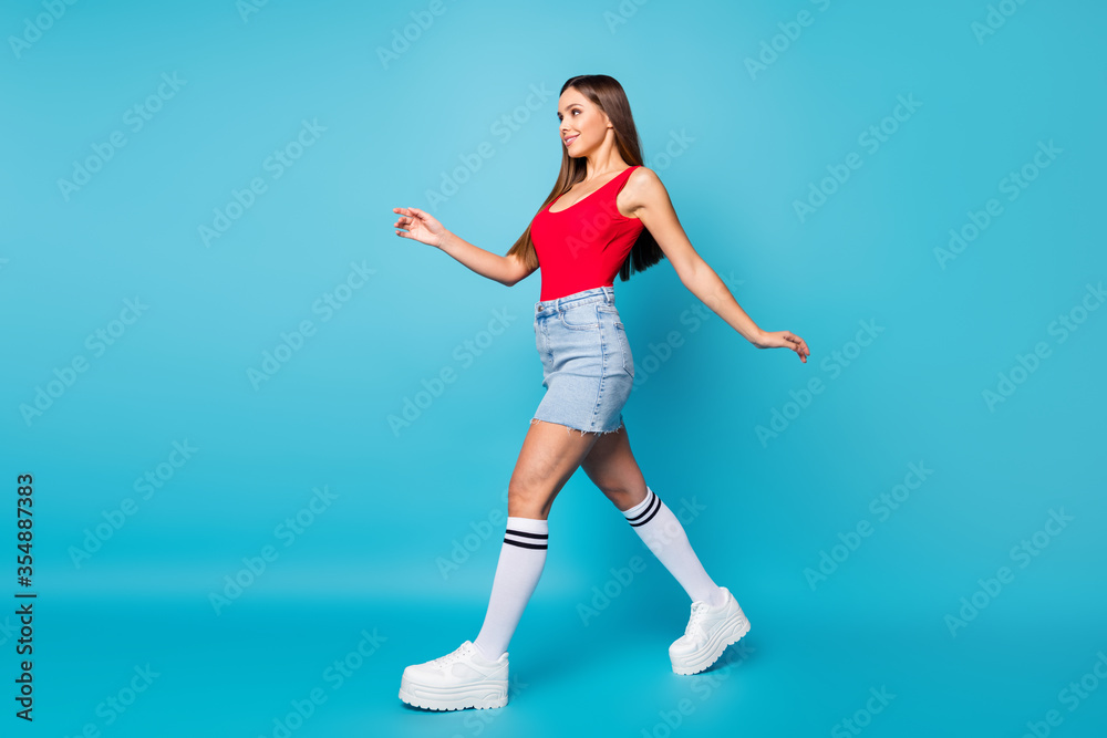 Full length profile side photo of candid lovely pretty girl walk go enjoy spring free time weekend wear singlet legs isolated over blue color background