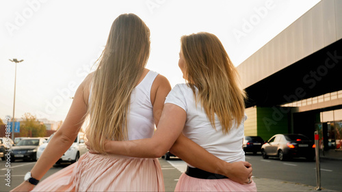 Rear view photo of two blonde girls embracing and olding each other at sunset photo