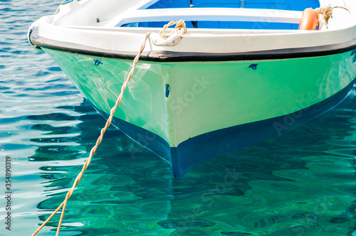 boat moored on turquoise waters in the old port of oia santorini © raulbachiller
