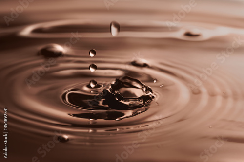 Splash of melted chocolate with drops as background, closeup