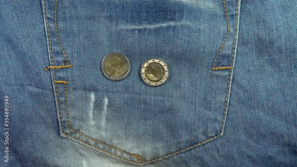 Euro coins falling in slow motion on a denim pants pocket Euro coins falling in slow motion on a denim pants pocket