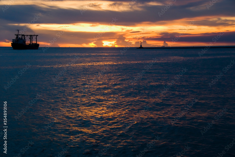 Sunset into the sea with the container ship silhouette.