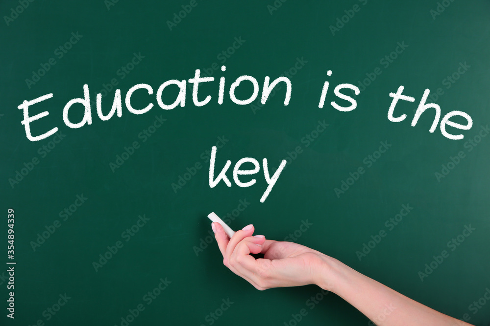 Woman writing phrase Education is the key on chalkboard, closeup. Adult learning Woman writing phrase Education is the key on chalkboard, closeup. Adult learning