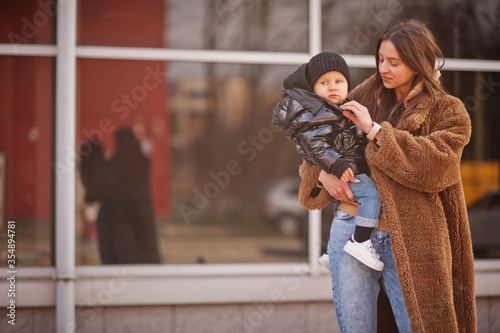 Young mother with child on hands walking down streets.