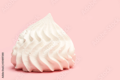Un malvavisco merengue blanco en primer plano sobre un fondo rosa liso y aislado. Vista de frente. Copy space