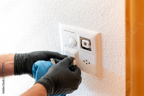 Photos close up of a professional cleaner cleaning a modern light switch and dimmer and