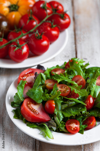 Healthy and light summer lunch: fresh green salad with ripe red tomatoes. Low calories delicious meal, vegan and vegetarian diet. Everyday source of vitamins