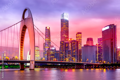 Guangzhou cityscape over Pearl River with Liede Bridge and illuminated financial district during beautiful colorful sunset. Guangzhou, Guangdong, Southern China.