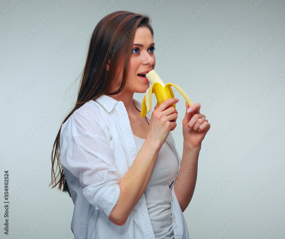 Woman in dressed casual eating banana and looking away. Woman in dressed casual eating banana and looking away.
