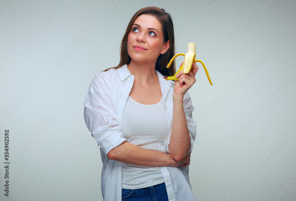 Woman dressed white shirt eating banana looking up. Woman dressed white shirt eating banana looking up.