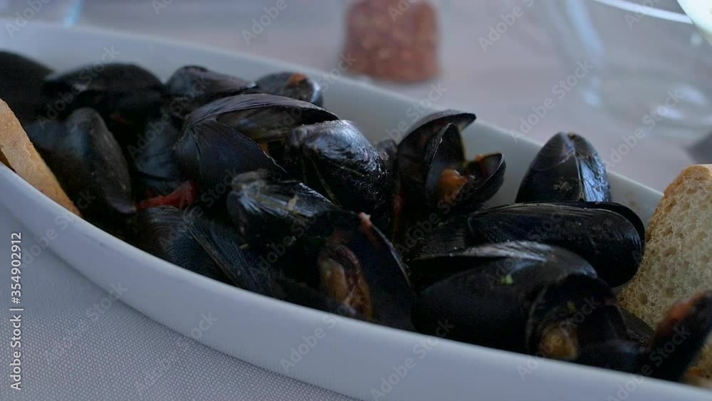 Sea mussels in a large plate cooked in tomato sauce and croutons. Traditional Italian dish seafood. The video has an artistic noise Sea mussels in a large plate cooked in tomato sauce and croutons. Traditional Italian dish seafood. The video has an artistic noise