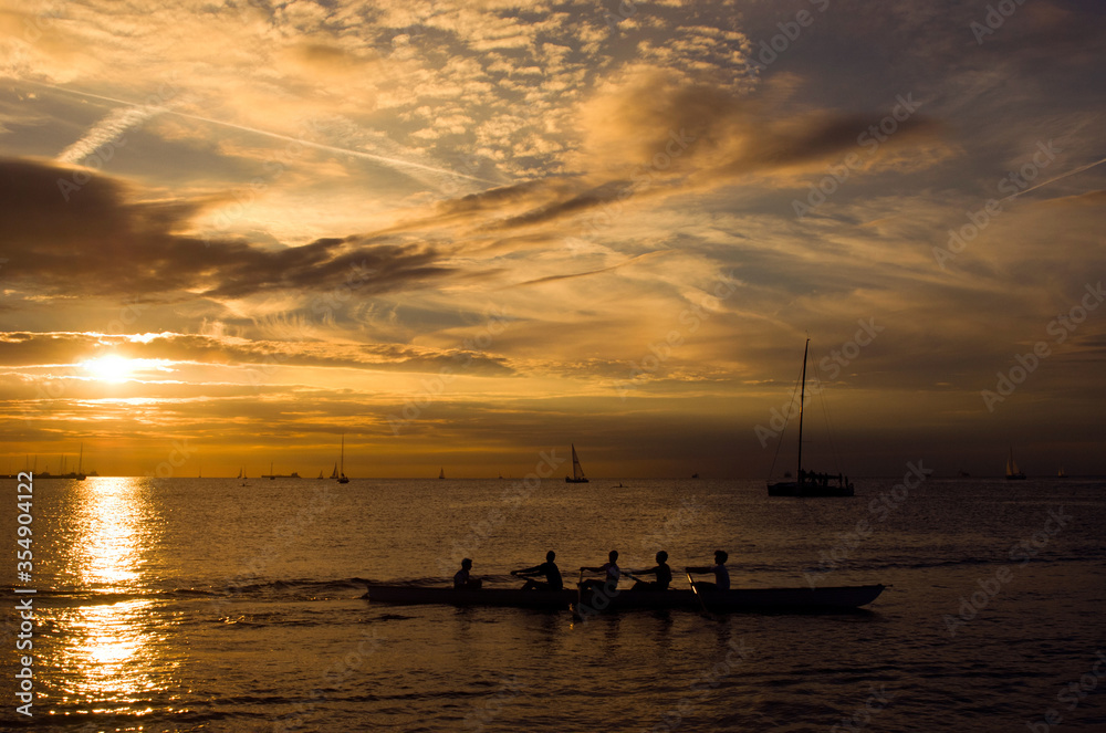 Sports team rowing in a canoe at sunset