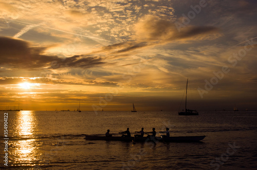 Sports team rowing in a canoe at sunset