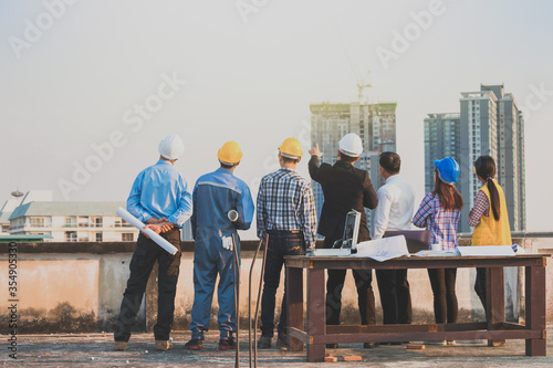 Businessman who point to target and engineer team at construction site and city scape background.