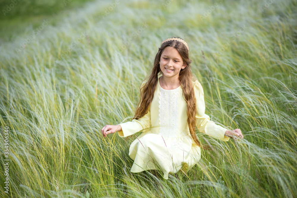 girl in a field. young woman in the field of flowers. 
Beautiful girl walks in the park. Summer walks and relaxation. Smiling child. Daisies in the hands of a girl - obrazy, fototapety, plakaty 