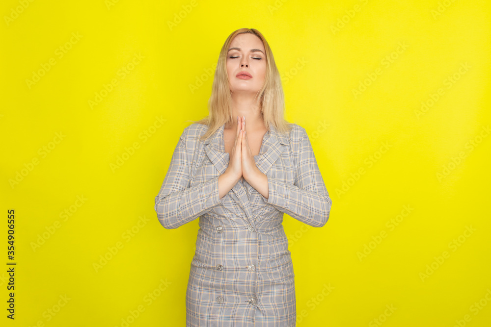 Attractive blonde woman in plaid jacket dress over yellow background Attractive blonde woman in plaid jacket dress over yellow background