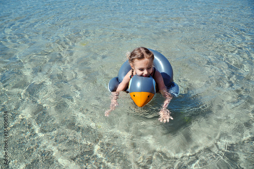 Little girl with rubber ring on beach.