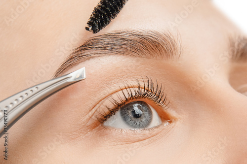 Vászonkép Master tweezers depilation of eyebrow hair in women, brow correction