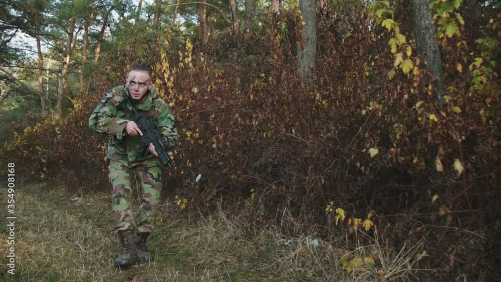 The hunter climbs out of the bushes and aims a gun at an object in the forest The hunter climbs out of the bushes and aims a gun at an object in the forest