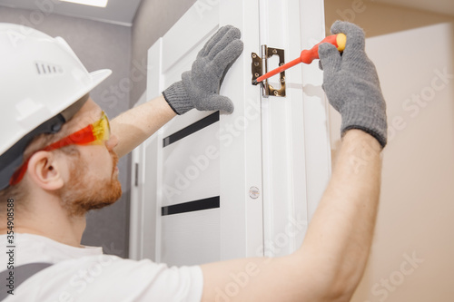 Obraz na plátně Male carpenter wood door installation working tightens lock
