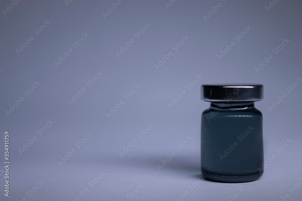 Little bottle with black liquid on white-gray background. Isolated. Board games. Cure - medicine, vaccine. Coronavirus or covid-19 - pandemic. High quality photo Little bottle with black liquid on white-gray background. Isolated. Board games. Cure - medicine, vaccine. Coronavirus or covid-19 - pandemic. High quality photo