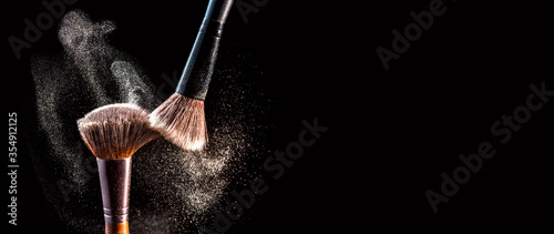 Valokuva Make up cosmetic brushes with powder blush explosion on black background