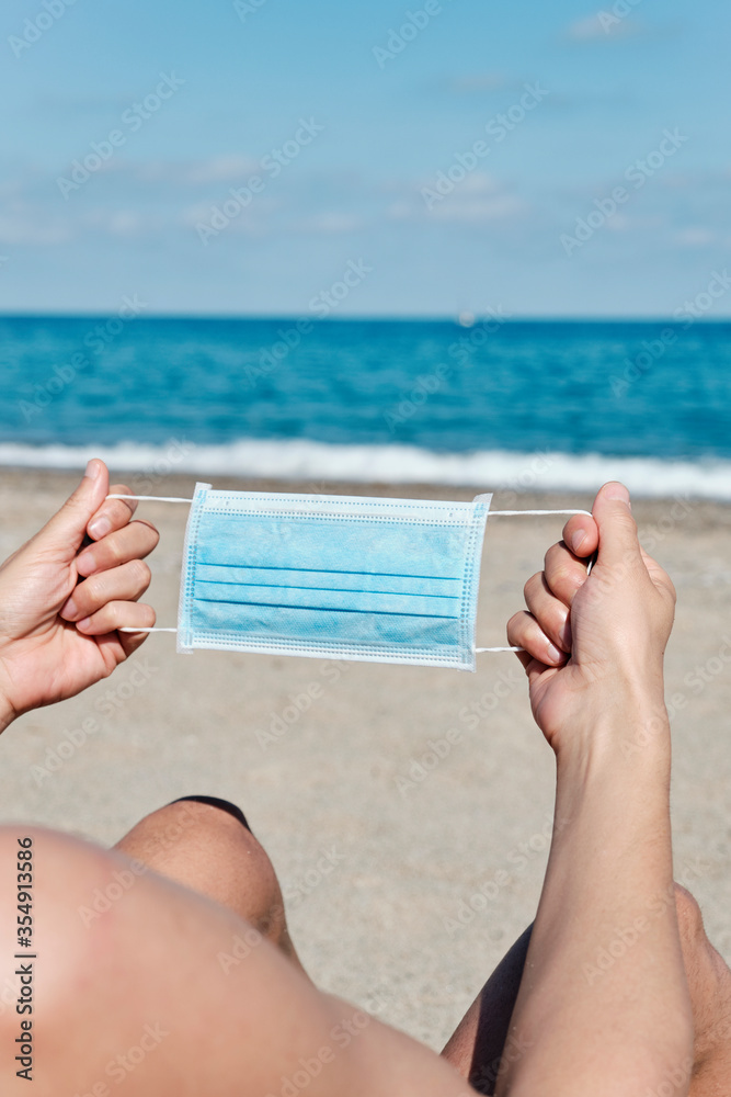 man with a surgical mask in his hands on the beach man with a surgical mask in his hands on the beach