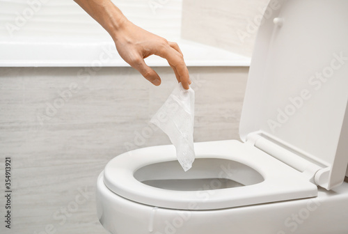 Hand throwing out toilet sheet in bowl