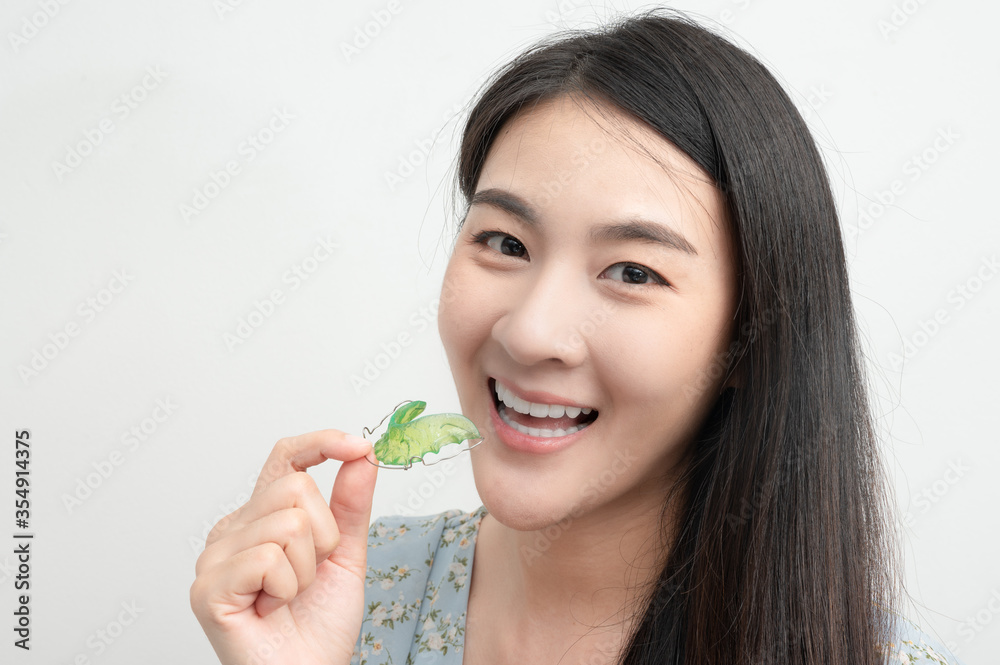 Asian woman holding orthodontic retainers.Teeth retaining tools after braces. concept Orthodontics Dental. Asian woman holding orthodontic retainers.Teeth retaining tools after braces. concept Orthodontics Dental.