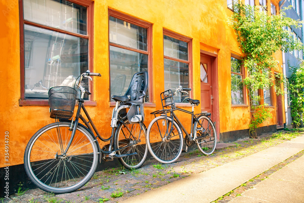 Old yellow house of Nyboder district with bicycles. Old Medieval district in Copenhagen, Denmark. Summer sunny day