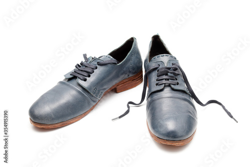 Two funny blue shoes with untied laces on a white isolated background