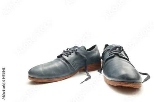 Two funny blue shoes with untied laces on a white isolated background