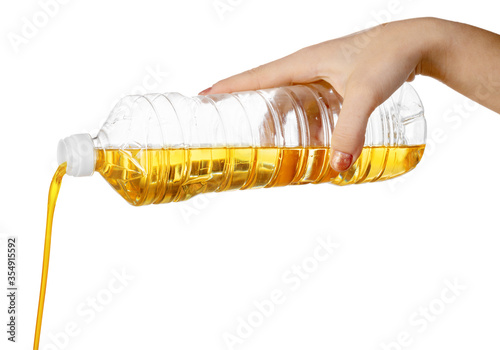 Hand of woman pouring cooking oil from plastic bottle. Isolated on white background.