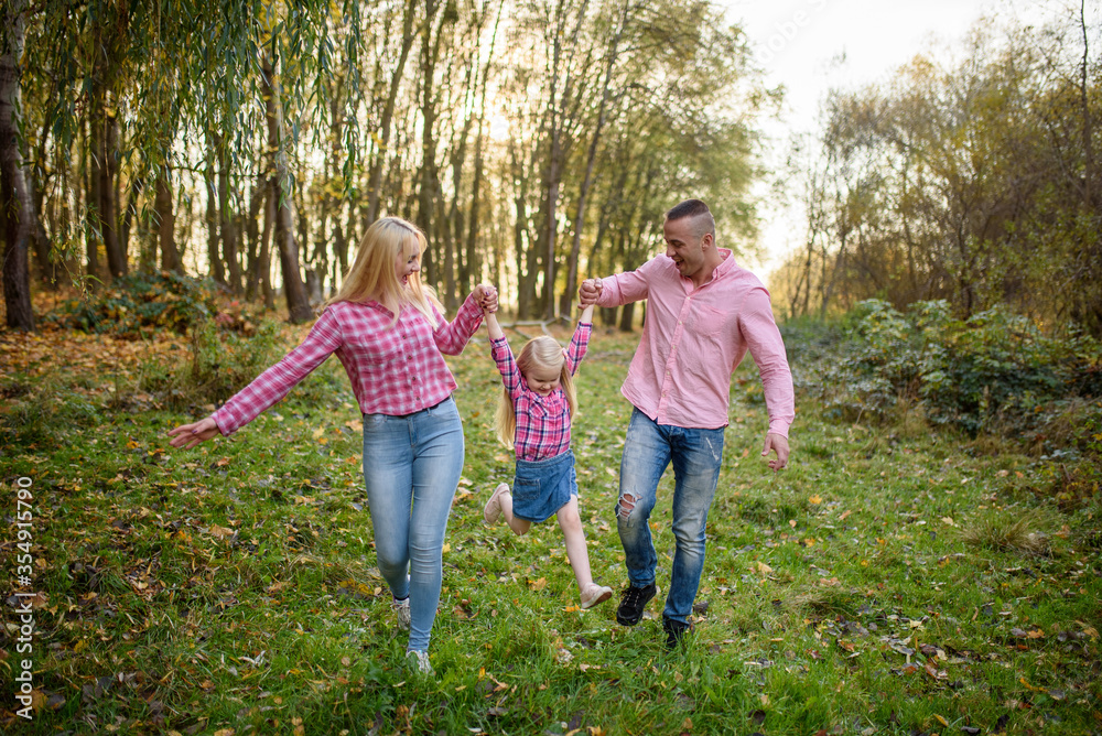 Fototapeta premium Father, daughter and mother walking outdoors. Happy family.